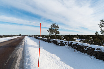 Image showing Straight country road with a snow stake by roadside