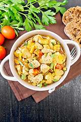 Image showing Chicken with vegetables and peas in saucepan on dark board top