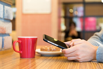 Image showing Woman sending sms on mobile phone in cafe