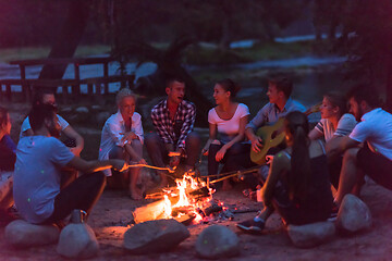 Image showing young friends relaxing around campfire