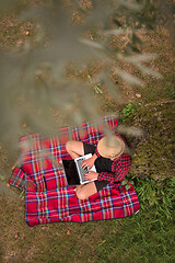 Image showing top view of man using a laptop computer under the tree