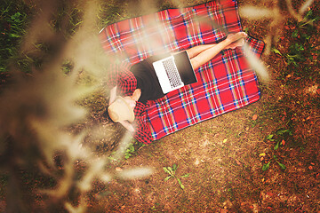 Image showing top view of man using a laptop computer under the tree