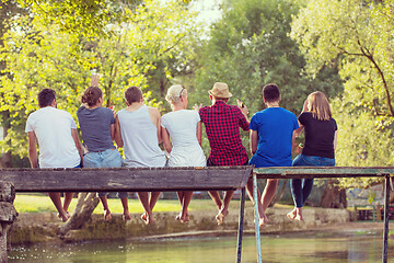 Image showing rear view of friends enjoying watermelon while sitting on the wo