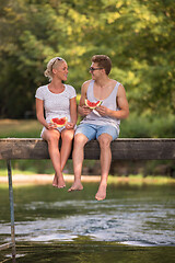 Image showing couple enjoying watermelon while sitting on the wooden bridge