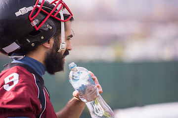 Image showing american football player drinking water after hard training