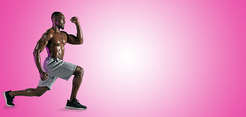 Image showing Young african-american bodybuilder training over pink background