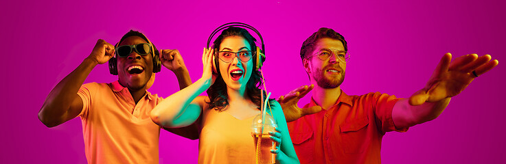 Image showing Beautiful young people in neon light isolated on pink studio background