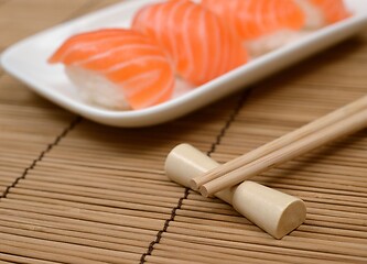 Image showing chopsticks and sushi with salmon on the mat