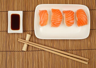 Image showing chopsticks, soy sauce and sushi with salmon on the mat