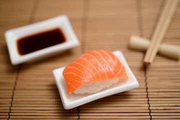 Image showing chopsticks, soy sauce and sushi with salmon on the mat