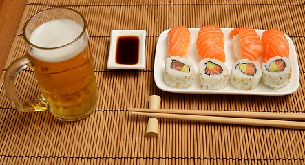 Image showing chopsticks, soy sauce, sushi and glass of beer on the mat