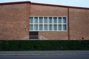 Image showing facade of a brick building with a large window, deadpan photo