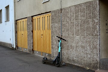Image showing an electric scooter is parked near the garage door of an buildin