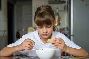 Image showing A schoolgirl came from school and sat down to eat at the table in the kitchen at home