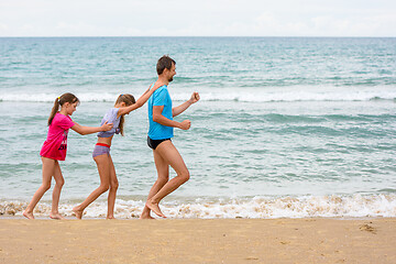 Image showing Dad and two children have fun running a little train along the seashore