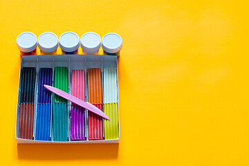 Image showing On a yellow background lies a box with plasticine and paint