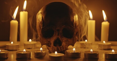 Image showing Candles and human skull in darkness closeup footage