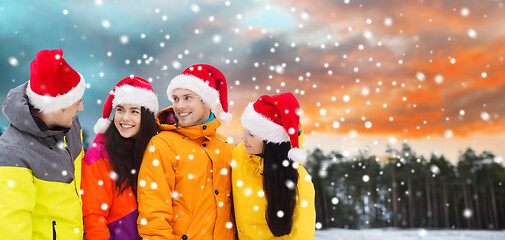 Image showing happy friends in santa hats and ski suits outdoors