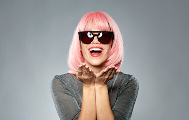 Image showing happy woman in pink wig holding something on palms