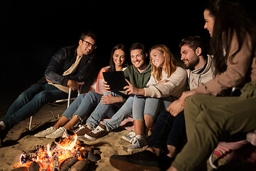 Image showing friends with tablet pc at fire on beach at night