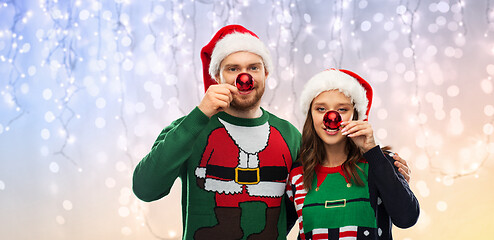 Image showing happy couple in christmas sweaters and santa hats