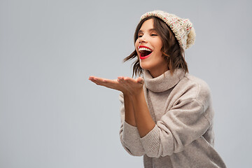 Image showing young woman in knitted winter hat sending air kiss