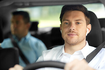 Image showing male driver with wireless earphones driving car