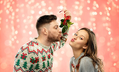 Image showing happy couple kissing under mistletoe on christmas