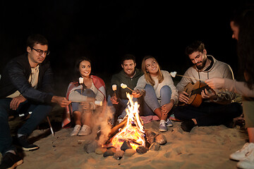 Image showing friends roasting marshmallow on camp fire on beach