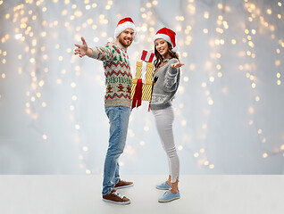 Image showing happy couple in christmas sweaters with gifts