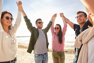 Image showing happy friends holding hands on summer beach