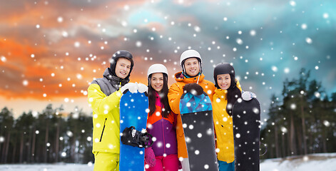 Image showing happy friends in helmets with snowboards outdoors