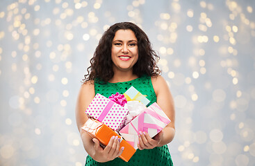 Image showing happy woman holding gift boxes over lights