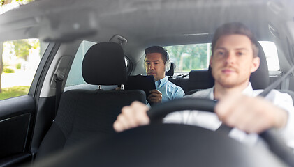 Image showing man with tablet pc and headphones riding in car