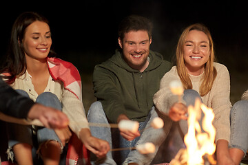 Image showing friends roasting marshmallow on camp fire at night