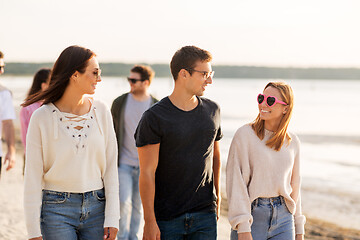 Image showing happy friends walking along summer beach