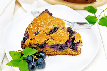 Image showing Pie with black grapes  in plate on wooden board