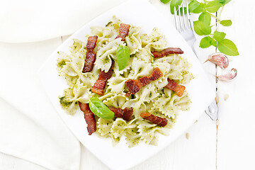 Image showing Farfalle with pesto and bacon in plate on board top