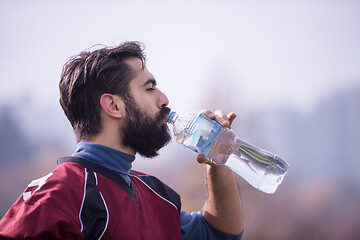 Image showing american football player drinking water after hard training