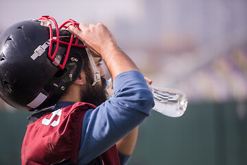 Image showing american football player drinking water after hard training