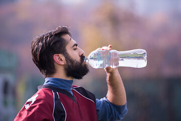 Image showing american football player drinking water after hard training