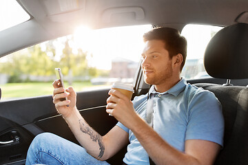 Image showing passenger drinking coffee using smartphone in car