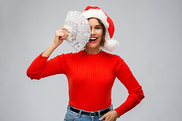 Image showing happy woman in santa hat with money on christmas