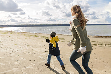 Image showing happy family running along autumn beach