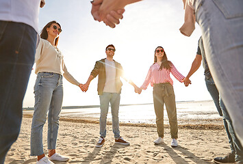 Image showing happy friends holding hands on summer beach