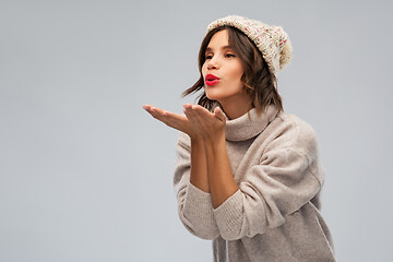 Image showing young woman in knitted winter hat sending air kiss