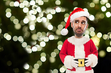 Image showing sad man in santa claus costume over christmas tree