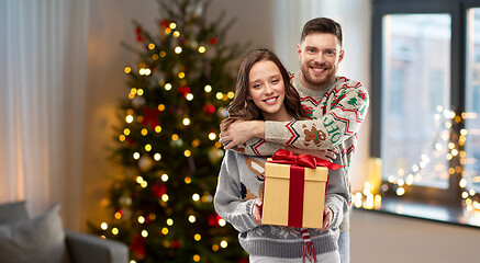 Image showing happy couple in christmas sweaters with gift box
