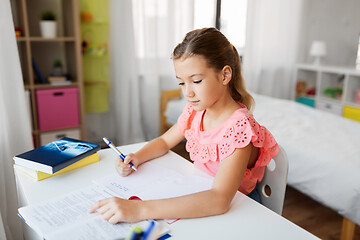 Image showing student girl with book writing to notebook at home