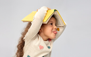 Image showing portrait of smiling girl with book on head